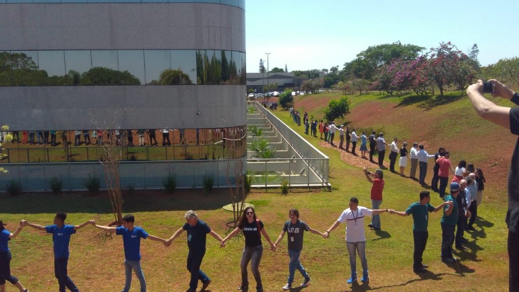 Vários pesquisadores de mãos dadas ao redor da sede do CNPq em um abraço simbólico